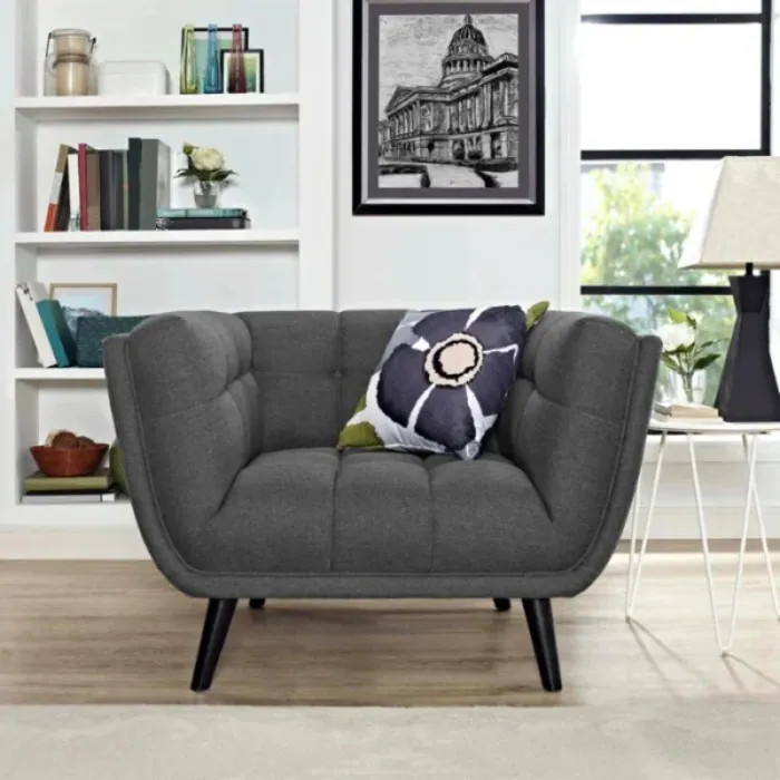 Bestow Upholstered Armchair Bestow Upholstered Armchair in grey fabric with deep tufting and tapered legs styled in living room.